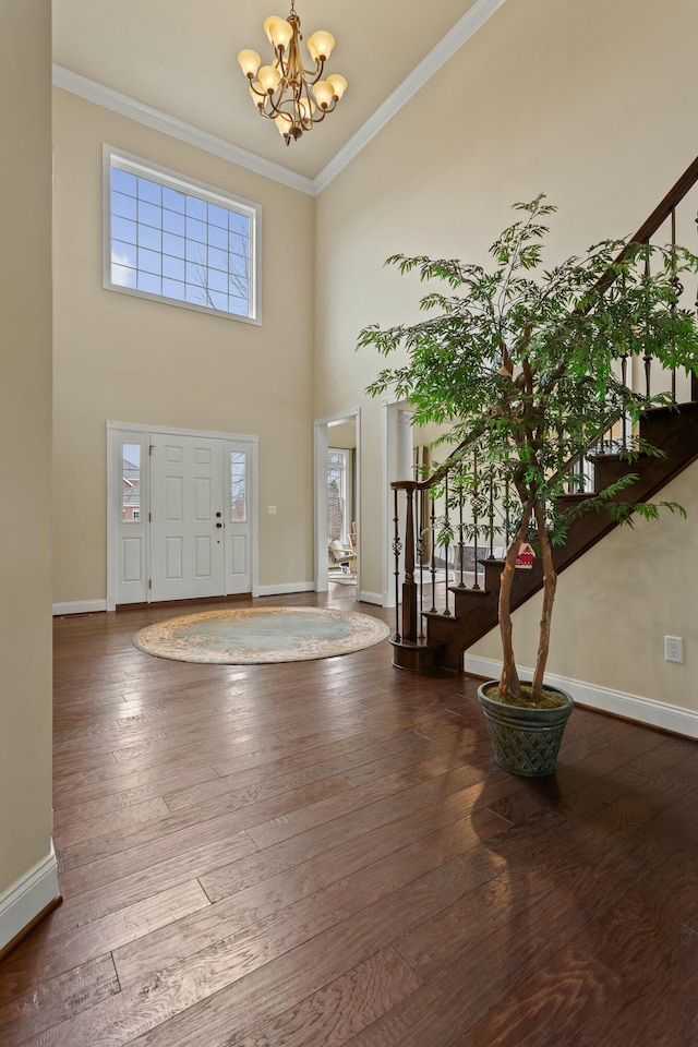 entryway featuring hardwood / wood-style flooring, stairs, crown molding, and an inviting chandelier