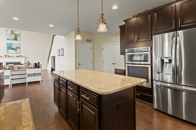 kitchen featuring dark wood-type flooring, a kitchen island, visible vents, open floor plan, and appliances with stainless steel finishes