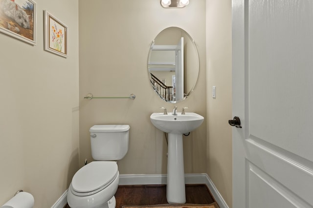 bathroom with toilet, baseboards, and wood finished floors