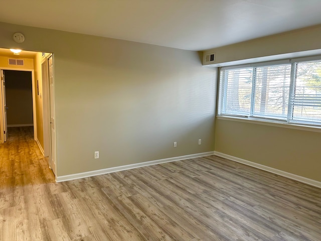 unfurnished room featuring wood finished floors, visible vents, and baseboards