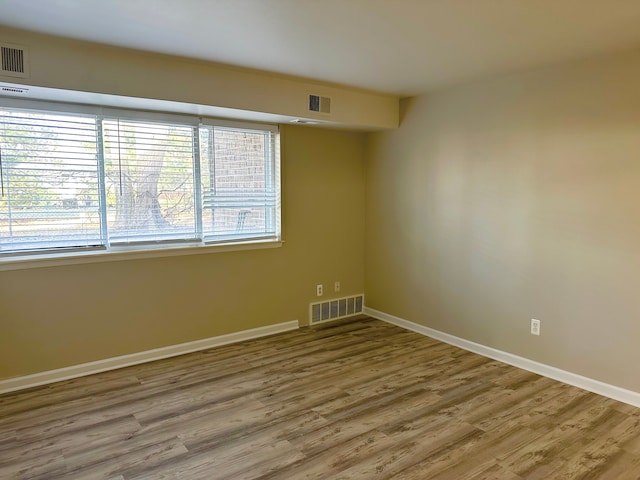 spare room with visible vents, baseboards, and wood finished floors