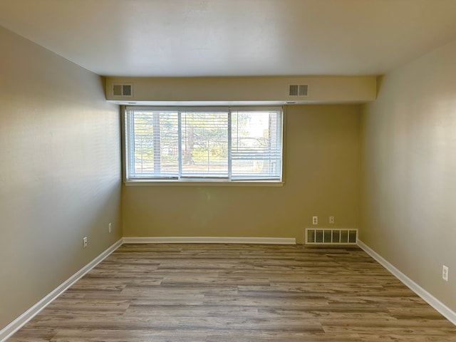 unfurnished room with baseboards, visible vents, and wood finished floors