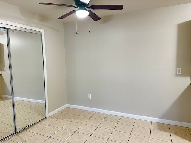 unfurnished bedroom with ceiling fan, a closet, light tile patterned flooring, and baseboards