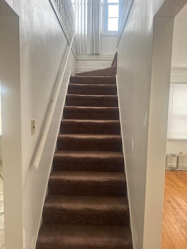 stairway with wood finished floors and baseboards