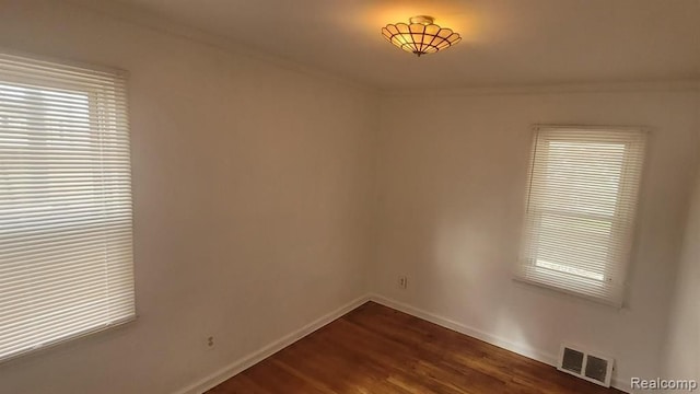 unfurnished room with baseboards, crown molding, visible vents, and dark wood-type flooring