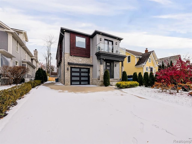 contemporary house featuring stone siding, a balcony, and an attached garage