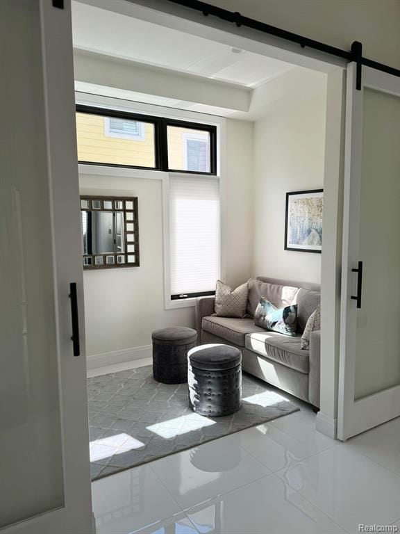 living area featuring tile patterned flooring, baseboards, and a barn door