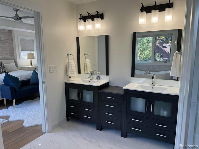 ensuite bathroom with a tub to relax in, marble finish floor, connected bathroom, vanity, and baseboards