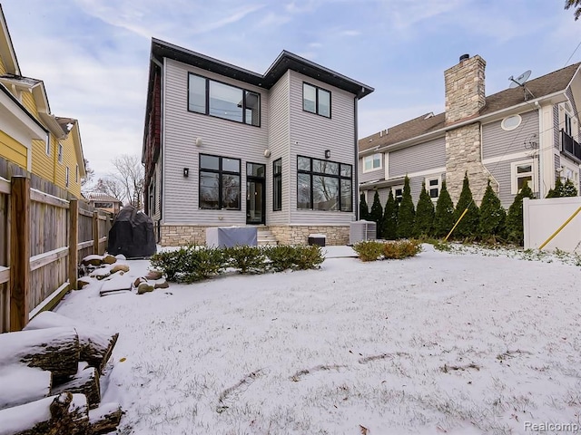 snow covered house with fence and central AC