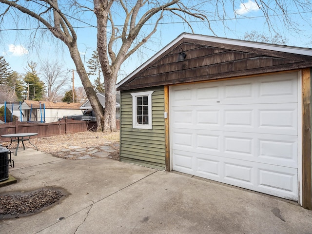 detached garage with concrete driveway and fence