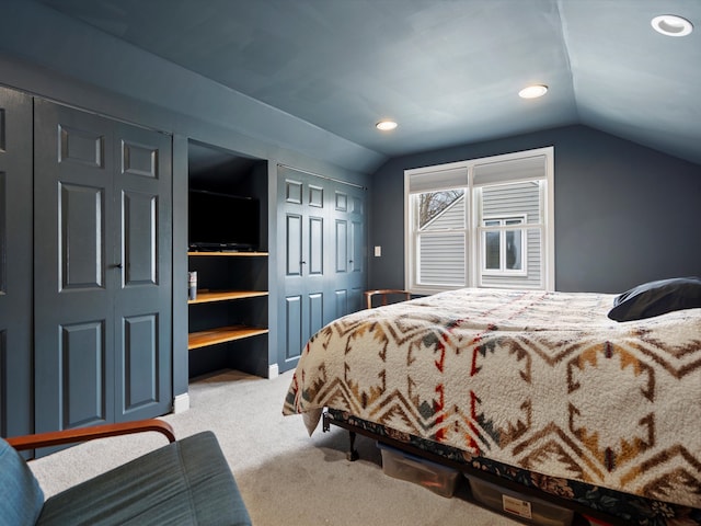 bedroom with carpet floors, vaulted ceiling, and two closets