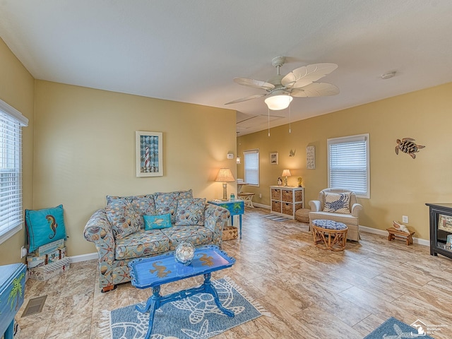 living room with baseboards, visible vents, and a ceiling fan