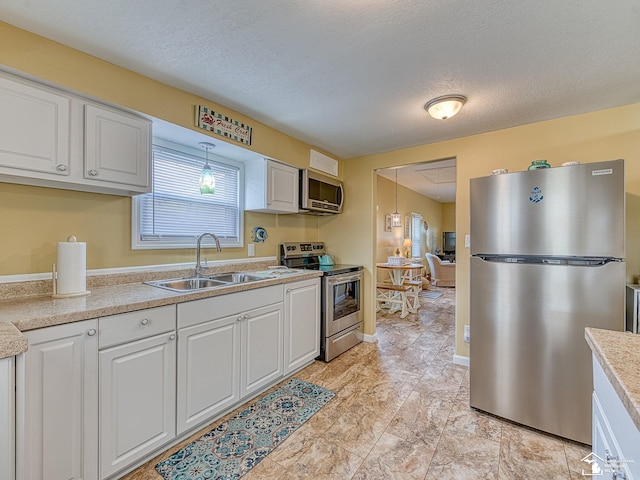 kitchen with light countertops, appliances with stainless steel finishes, a sink, and white cabinets