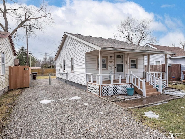 view of front of property with a shingled roof, covered porch, a gate, fence, and driveway