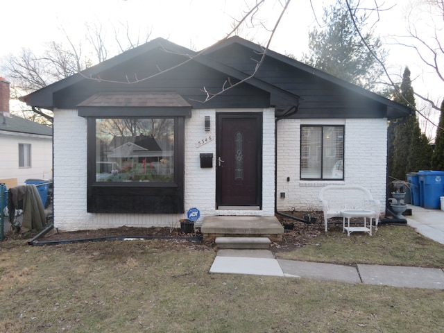 bungalow-style house with brick siding and a front yard