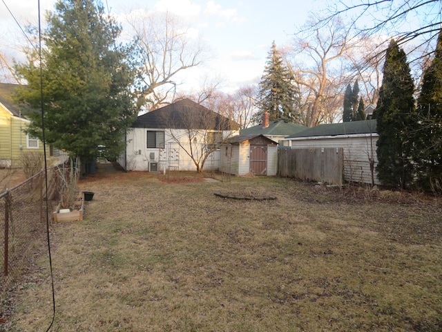 view of yard featuring an outbuilding, a storage unit, and fence