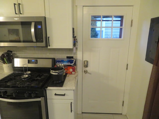 kitchen with electric panel, backsplash, white cabinets, and stainless steel appliances