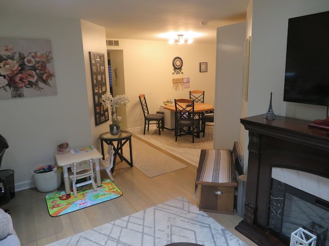 living area featuring visible vents, baseboards, wood finished floors, and a fireplace