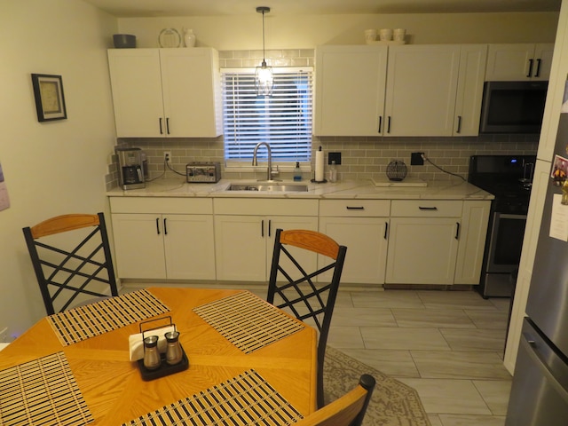 kitchen with backsplash, stainless steel electric range, hanging light fixtures, white cabinetry, and a sink