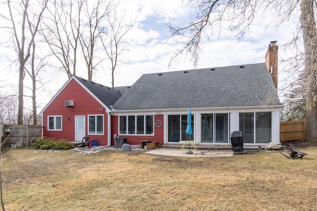 rear view of house featuring entry steps, a shingled roof, fence, a yard, and a chimney