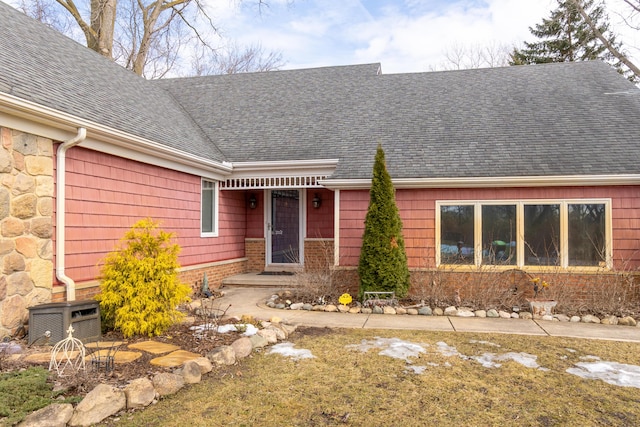 view of front of house featuring stone siding, a shingled roof, and brick siding