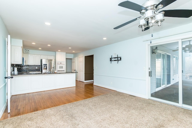 interior space with white cabinets, white oven, stainless steel refrigerator with ice dispenser, tasteful backsplash, and dark countertops