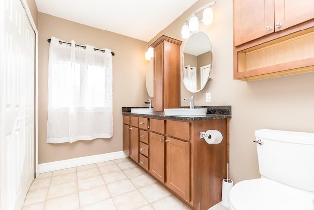 bathroom featuring baseboards, a sink, toilet, and double vanity