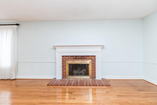 unfurnished living room with a fireplace, baseboards, and wood finished floors