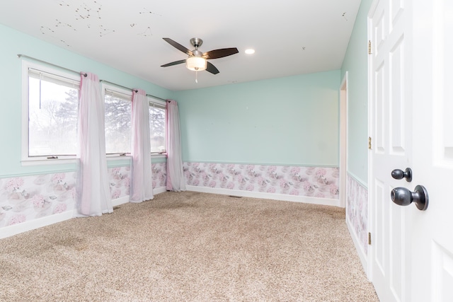 spare room featuring carpet floors, a ceiling fan, baseboards, and wallpapered walls