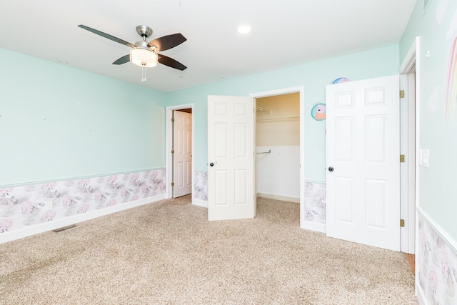 unfurnished bedroom featuring baseboards, visible vents, a walk in closet, carpet flooring, and a closet