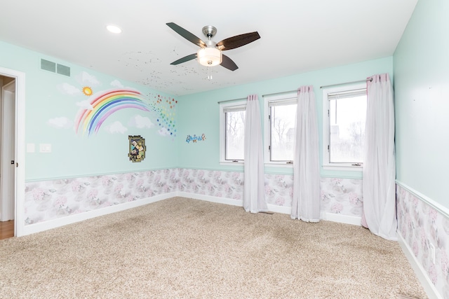 empty room with carpet floors, visible vents, ceiling fan, baseboards, and wallpapered walls