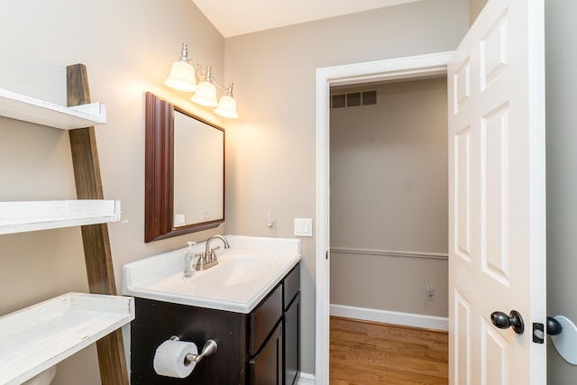 bathroom featuring baseboards, visible vents, wood finished floors, and vanity