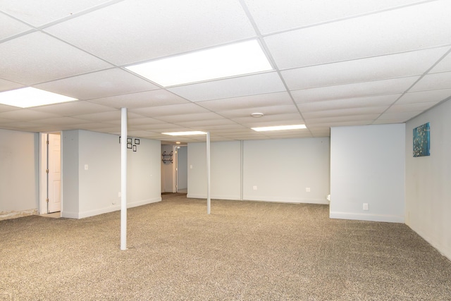 finished basement with a paneled ceiling, carpet flooring, and baseboards