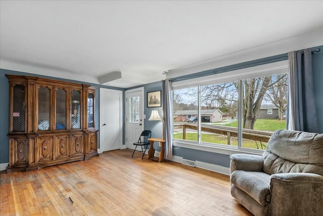 sitting room with light wood-type flooring, plenty of natural light, visible vents, and baseboards