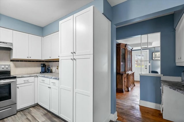 kitchen with electric stove, wood finished floors, white cabinetry, and decorative backsplash