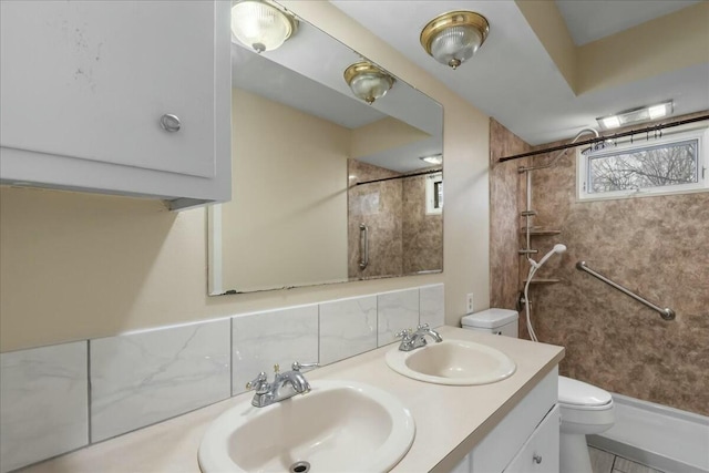 bathroom featuring toilet, a shower, decorative backsplash, and a sink