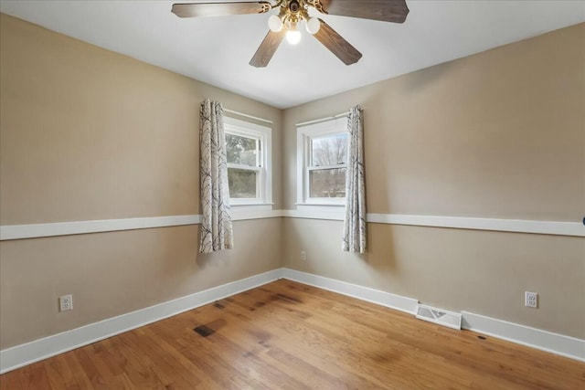 spare room with visible vents, ceiling fan, baseboards, and wood finished floors