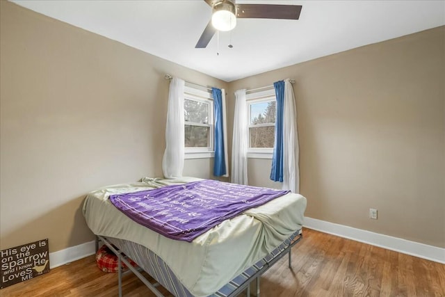 bedroom with ceiling fan, wood finished floors, and baseboards