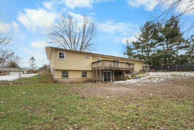 back of property with a yard, a wooden deck, and fence