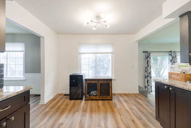 office featuring light wood-style flooring, an inviting chandelier, and baseboards