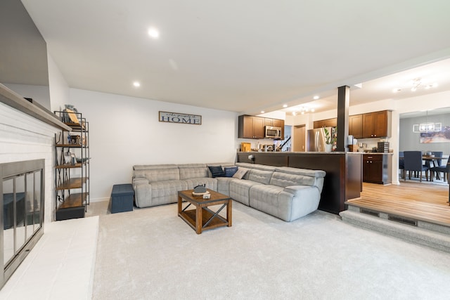 living room featuring a glass covered fireplace, recessed lighting, light colored carpet, and baseboards