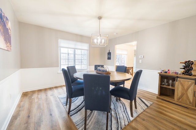 dining space featuring baseboards, a notable chandelier, and wood finished floors