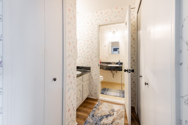 bathroom with wallpapered walls, vanity, toilet, and wood finished floors