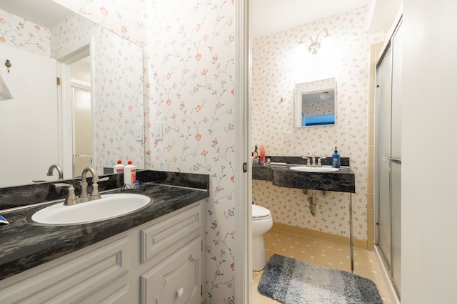 full bath featuring a sink, toilet, a stall shower, and wallpapered walls