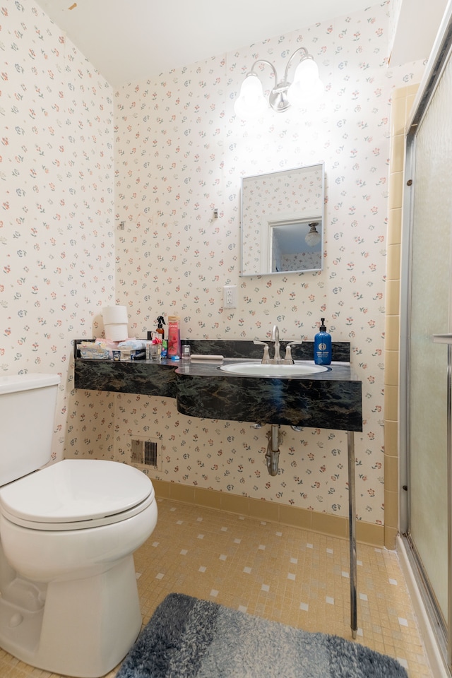 full bathroom with a sink, toilet, a shower stall, and wallpapered walls