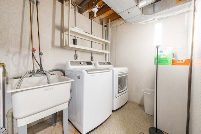 laundry area featuring laundry area, separate washer and dryer, light floors, and a sink