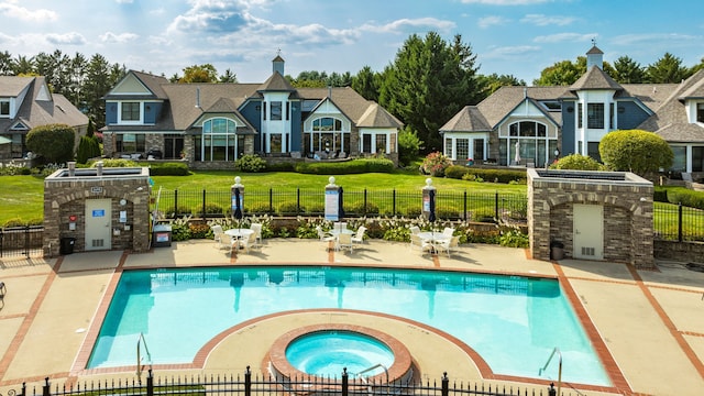 community pool featuring a patio area, a yard, a hot tub, and fence