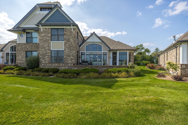 rear view of house featuring a yard and brick siding