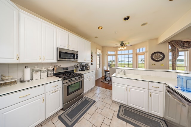 kitchen with stainless steel appliances, a wealth of natural light, white cabinetry, and backsplash