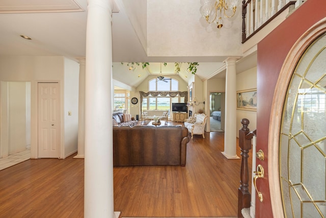 living room with lofted ceiling, decorative columns, an inviting chandelier, and wood finished floors